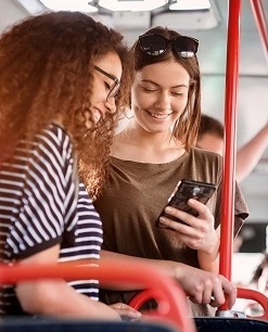 Two female bus passengers looking at a phone