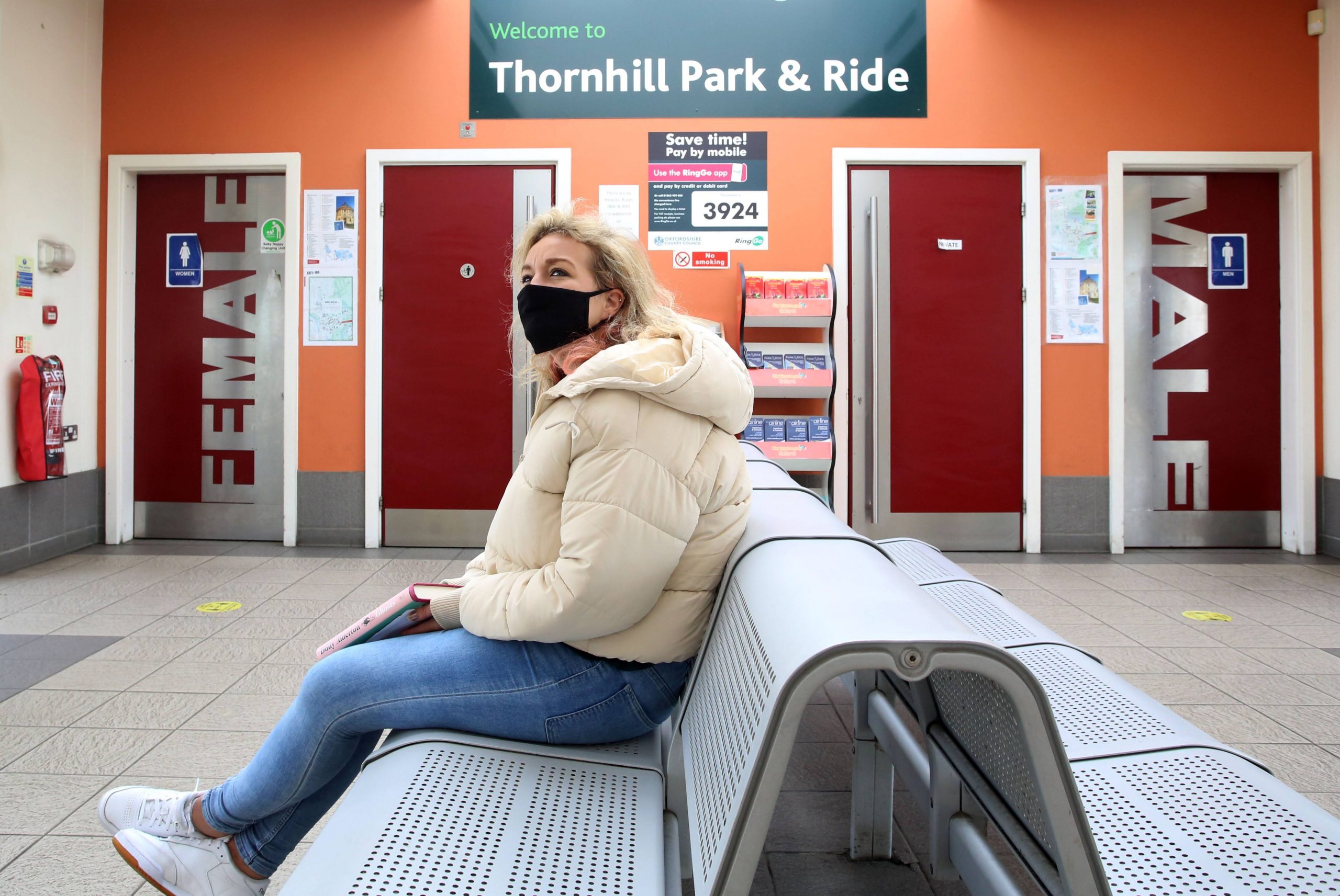 Woman in mask waiting on seat at Park and Ride stop