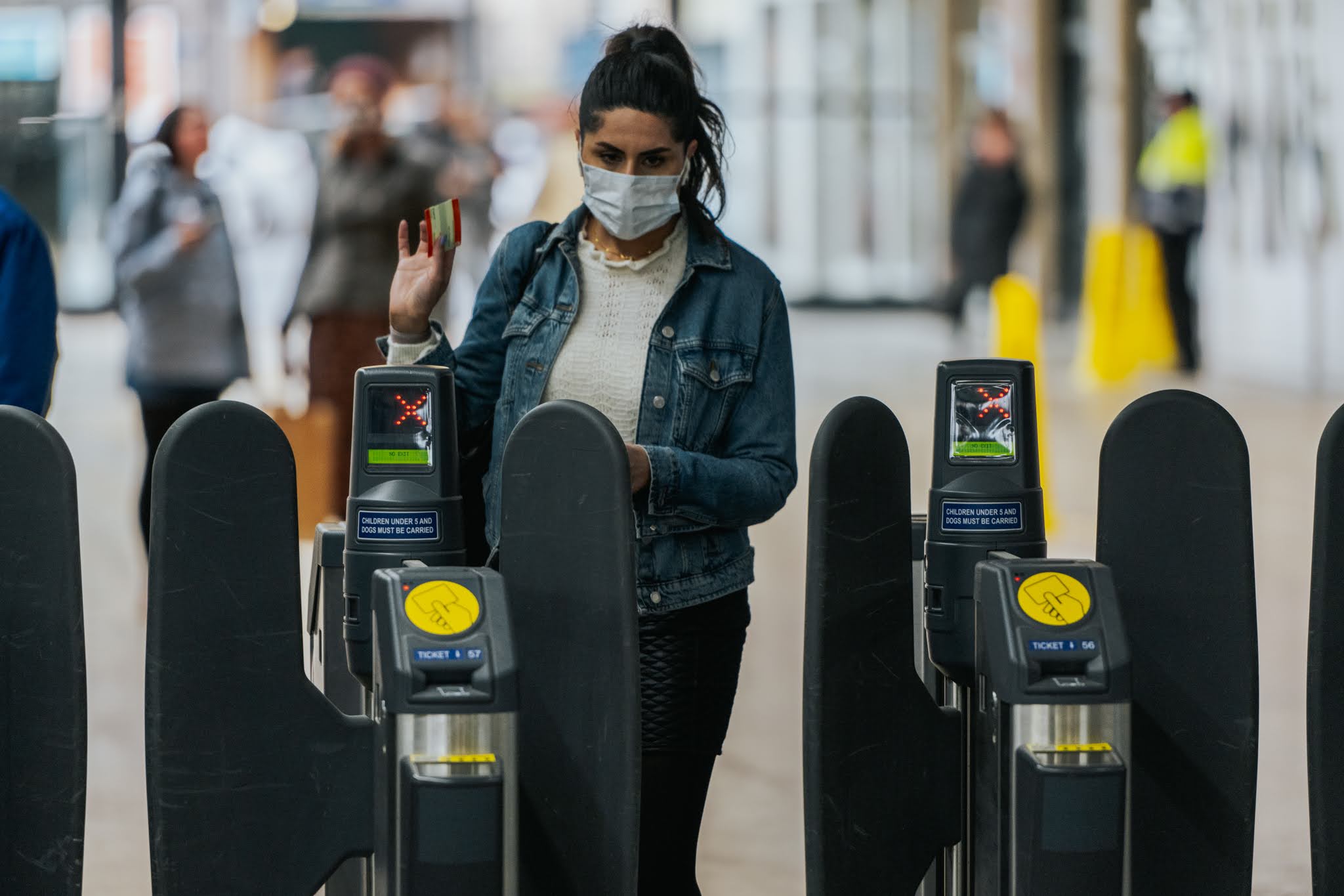 Woman in mask walking through ticket barrier