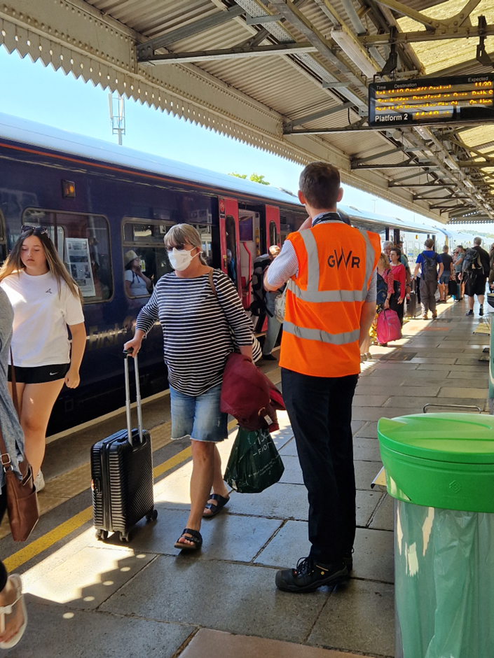 Passengers and a staff member standing by train on platform