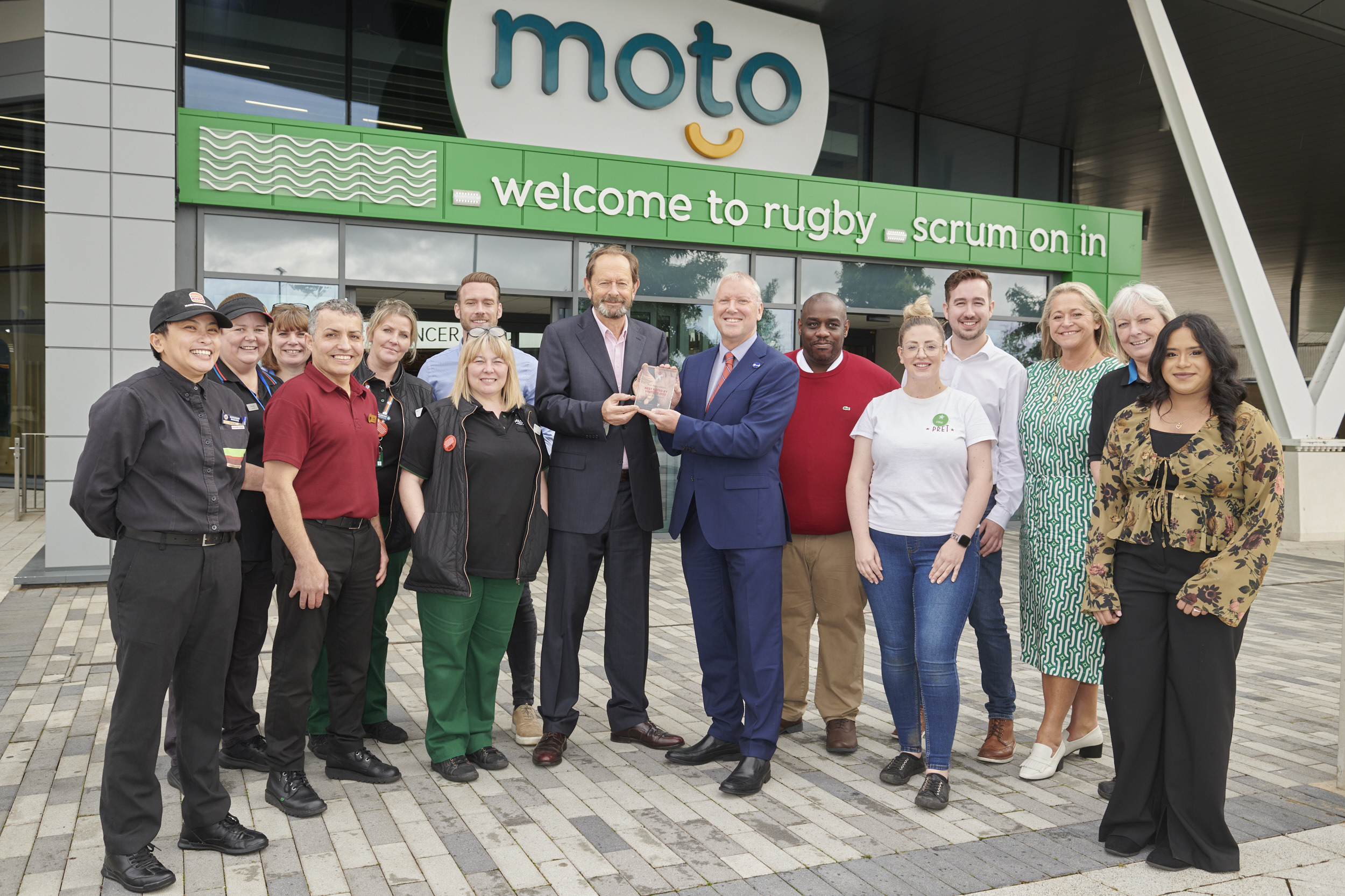 A picture of Anthony Smith, CEO of Transport Focus, presenting an award to Moto staff on winning the best motorway services 2023.